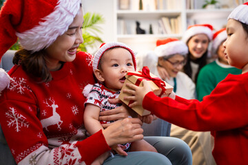 Asian family on Christmas Day. Everyone is happy together in a Christmas themed room filled with presents and orange lights.