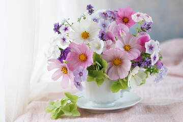 Beautiful still life with a bouquet in a cup, cosmos flowers, phlox, hydrangea, sweet peas, bellflower, lavender.