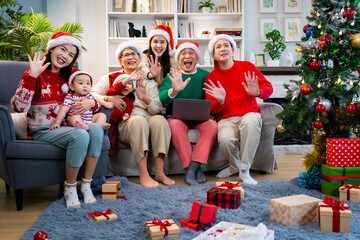 Asian family on Christmas Day. Everyone is happy together in a Christmas themed room filled with presents and orange lights.