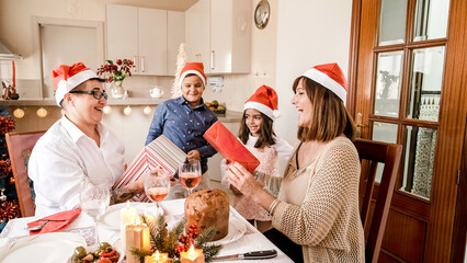 Lesbian couple in santa hat while kids carrying christmas gifts at home