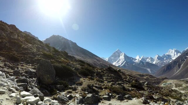 Panoramic view of mountain valley and footpath in Himalayas with Ama Dablam mountain in front and Mounts Cholatse and Tobuche in the right in sunny morning on Lukla - Everest base camp trekking route.