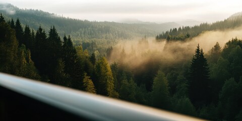 A scenic view of mist-covered rolling hills, densely forested and lush, as seen from a vantage point. Captured during early morning, this image exudes calm and natural beauty.