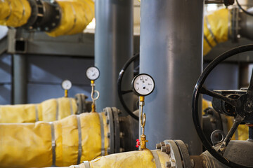Pipes, shut-off valves and pumps of the heating system in an industrial boiler room