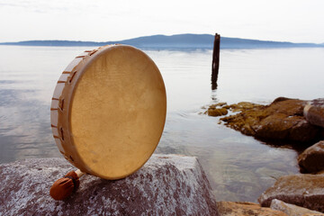 A vintage style image of a handmade leather meditation drum and leather rattle.