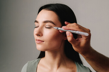 Surgeon is planning upper blepharoplasty with marker. Surgeon is drawing marking lines on eyelid of...