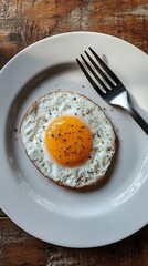 Fried egg on a white plate with pepper seasoning, breakfast concept