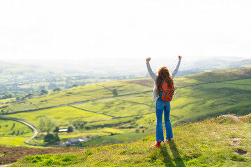 Woman Celebrating on Hilltop With Panoramic View of Rolling Green Hills During Daytime Adventure