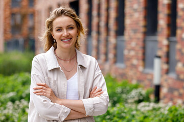 Portrait of a smiling woman standing with arms crossed on a city street