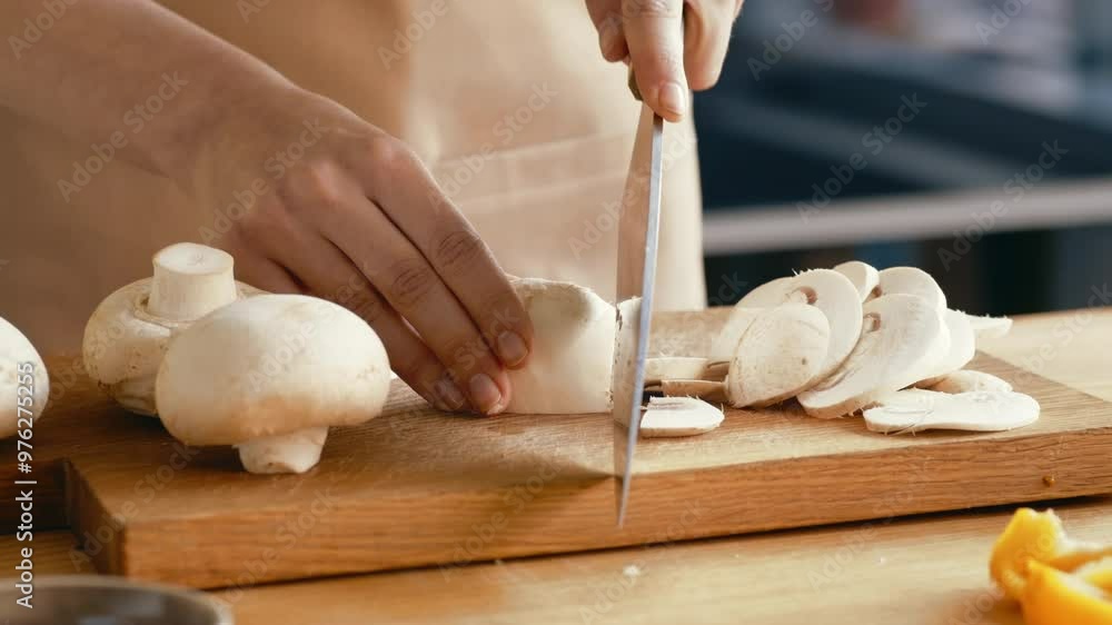 Sticker female hands slicing champignon mushrooms with kitchen knife on wooden cutting board, closeup