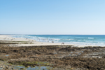 La plage de Penhors en Bretagne, anim&eacute;e par une belle journ&eacute;e d'&eacute;t&eacute;, avec de nombreux baigneurs dans l'oc&eacute;an Atlantique et des gens profitant du sable.