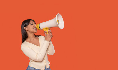 Woman Enthusiastically Shouting Into Megaphone Against  Vibrant Orange Backdrop
