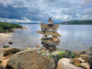cairn built in a complicated pattern with lake and sky in the background