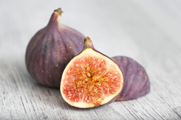 Fresh fig sliced in half closeup. Fruit's intricate texture. Single object isolated on a grey wooden background. Macro shot capturing the rich details of the fig's interior. Fruit cross section.