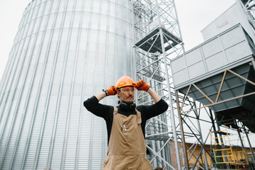 A male worker, in front of grain silos.