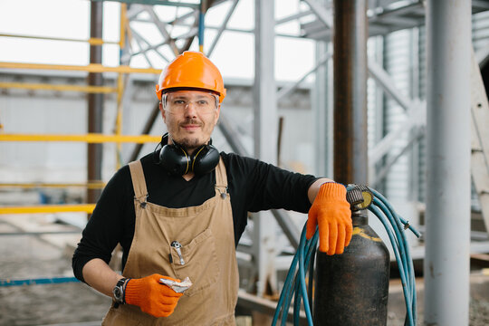 The assembly worker stands near the autogen on the construction site. A look at the camera.