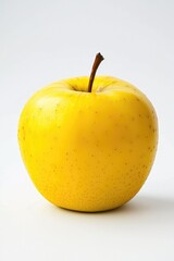 A single yellow apple sitting on a white surface, ideal for food-related photography and illustration