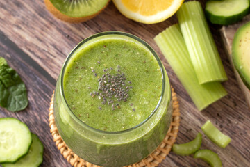 Green smoothie with celery, cucumber, kiwi and chia seeds on rustic wooden table. Top view. Healthy...
