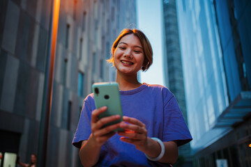 Nighttime Connection: Portrait of a 20 years Asian young girl engrossed in her smart phone to...