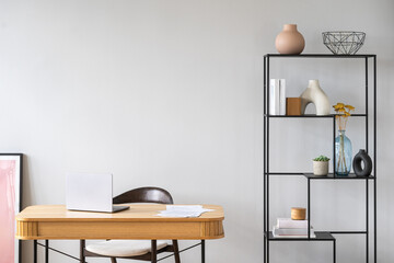 Wooden desk with laptop close to minimalist decor on black shelving © brizmaker