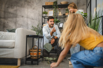 Father discusses broken vase with daughters in modern living room