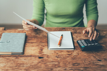 Balancing the Books: A woman meticulously manages her finances, calculating expenses with focused...
