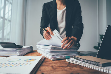 Businesswoman at Desk: A focused businesswoman meticulously examines documents in a well-organized...