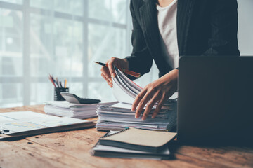 Overwhelmed by Paperwork: A businesswoman grapples with a mountain of files, her frustration...