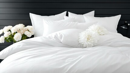   White sheets and pillows adorn a bed with a vase of flowers on the side and a black headboard