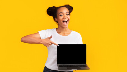 Awesome Application Or Website. Excited black girl showing blank laptop screen for advertising,...