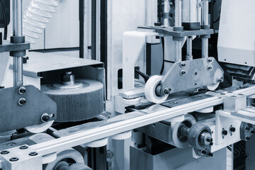 A machine is in the process of cutting a piece of wood. The machine has a large grinding wheel and a white wheel