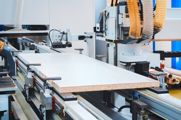 A woodworking shop with a large machine cutting a piece of wood. The machine is surrounded by a lot of dust and debris