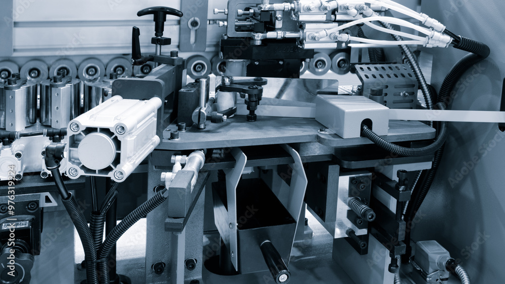 Poster a machine is cutting a strip of wood. the machine is surrounded by other machines