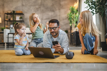 Family time with dad and daughters around laptop and mobile phone fun