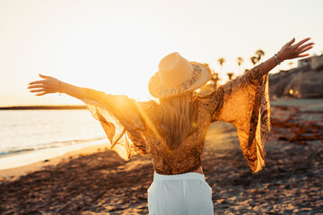 One happy beautiful woman walking on the sand of the beach enjoying and having fun at the sunset of the day. Leisure time on vacations, freedom concept.