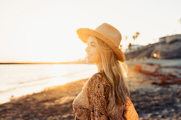 One happy beautiful woman walking on the sand of the beach enjoying and having fun at the sunset of the day. Looking at the sea smiling..