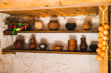 Antique clay, metal and birch bark pots on shelves in a village house