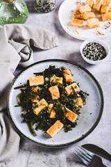 Seaweed salad with fried soy tofu cheese on plate on table vertical view