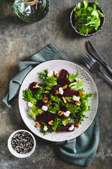 Beetroot salad with cheese, nuts and herbs on a plate on the table top and vertical view