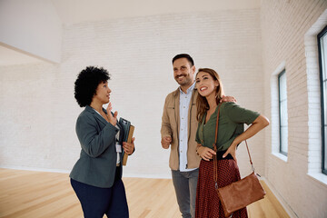 Real estate agent communicating with  couple while showing them new house for sale.