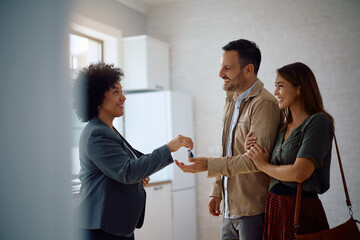 Happy couple receiving new house keys form real estate agent. Copy space.