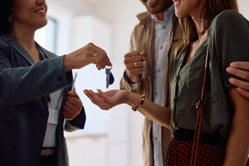 Close up of real estate agent giving new house keys to a couple of buyers.