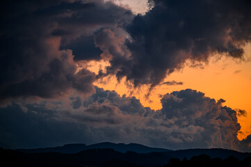 Dramatic Sunset Sky with Orange Glow and Dark Clouds Over Forest