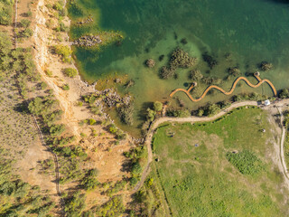 Aerial drone photo of Quarry turquiose lake colour, open pit mining in Park Grodek, Jaworzno. Poland. Turquiose Water and Wooden Bridge on lake. Polish Maldives Park Grodek in Jaworzno from drone.