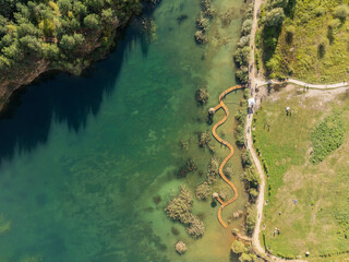 Aerial drone photo of Quarry turquiose lake colour, open pit mining in Park Grodek, Jaworzno. Poland. Turquiose Water and Wooden Bridge on lake. Polish Maldives Park Grodek in Jaworzno from drone.
