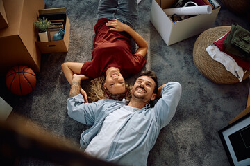 Above view of happy couple resting on floor at their new home.