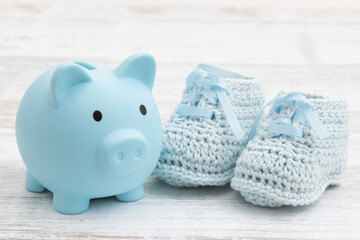 Childcare expense blue baby booties with a piggy bank on weathered wood