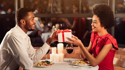 Happy Black Man Giving Gift To Girlfriend Celebrating Valentine In Fancy Restaurant. Panorama