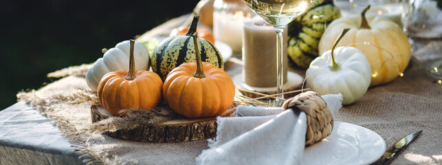 Fall still-life. Orange pumpkins, dry flowers and candles on linen tablecloth. Dinner table outdoors in the garden. Cozy autumn concept., simple handmade decoration, countryside style banner
