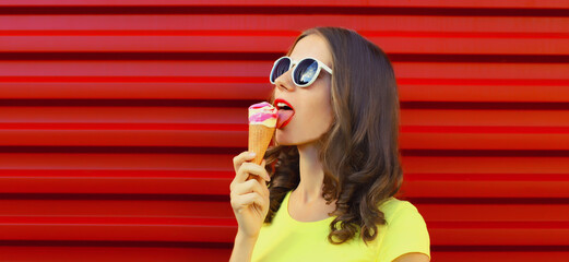 Summer portrait of happy young woman enjoying eating ice cream on red background
