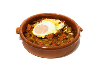 Vegetable ratatouille with a fried egg on top, served in a clay bowl. Isolated on a white...